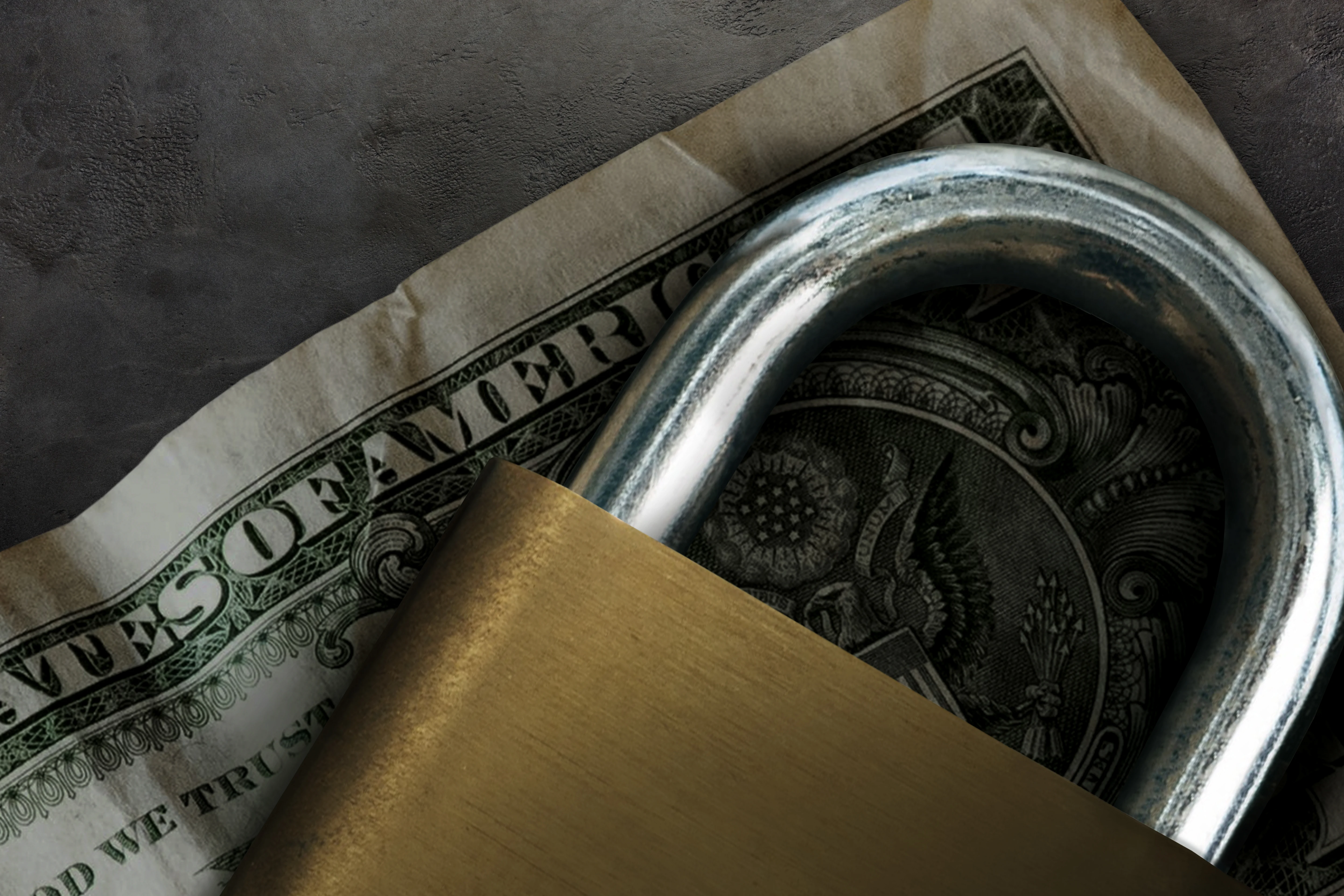 A closed padlock over top a USA one dollar bill.